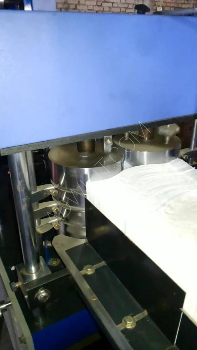 A machine for folding paper napkins into a square shape